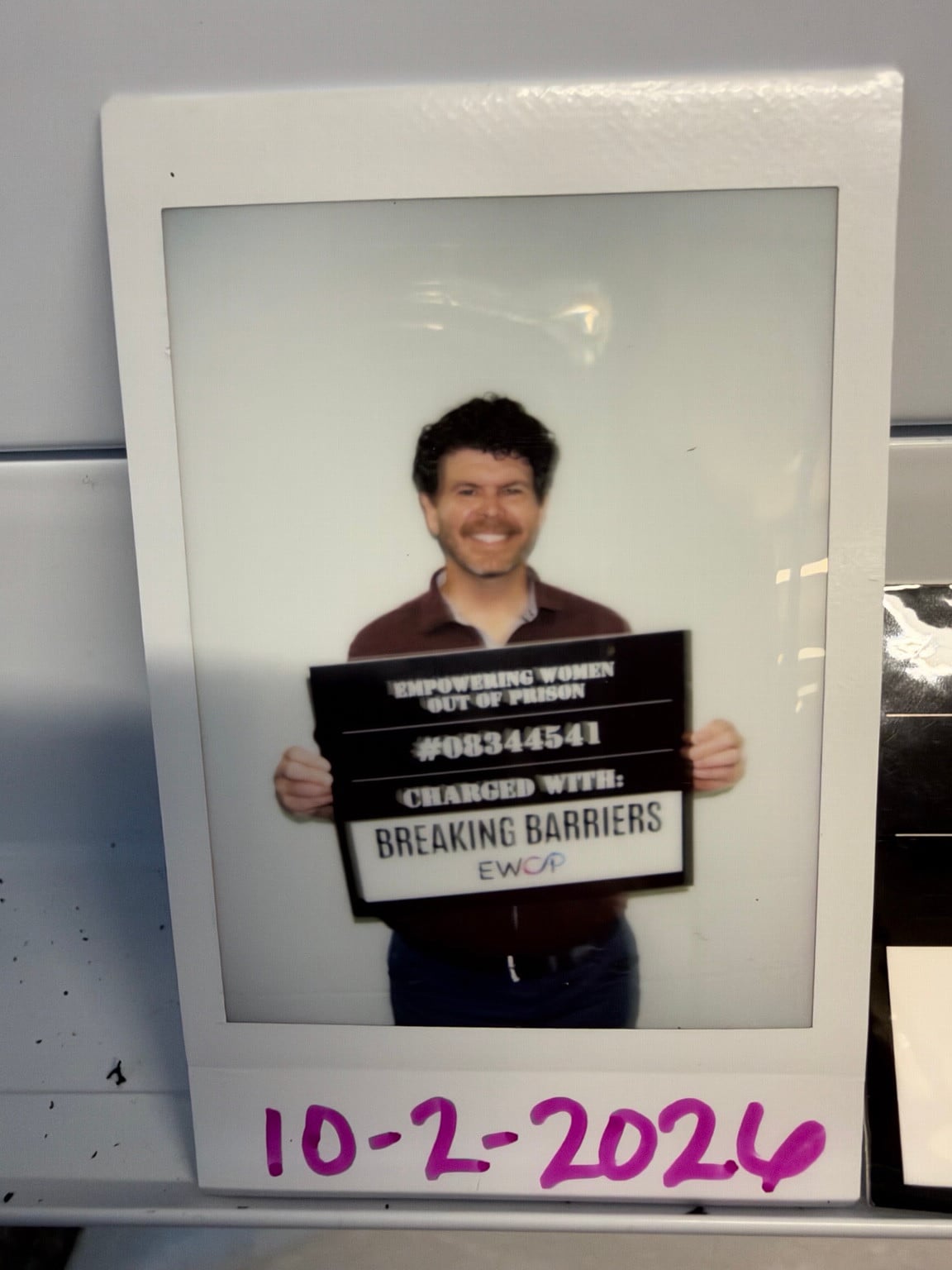 A printed portrait of a person holding an EWOP sign that reads Breaking Barriers.